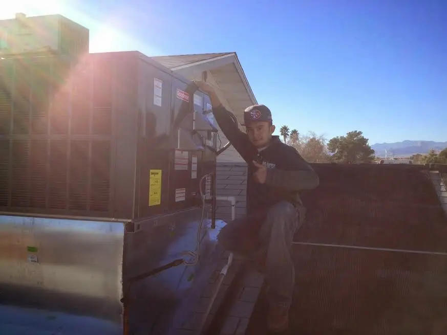 HVAC technician performing Air Duct Cleaning on a rooftop unit in Los Altos
