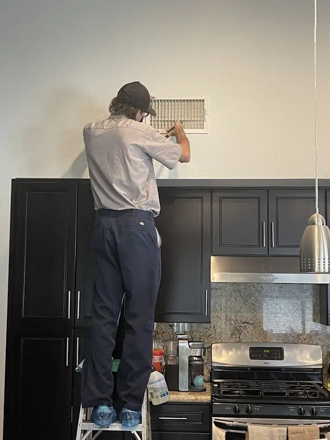 Technician inspecting an air vent during HVAC service in Los Altos